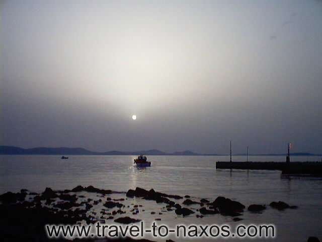 NAXOS PORT - Fishing boat leaveing Naxos Chora port at the sunset.